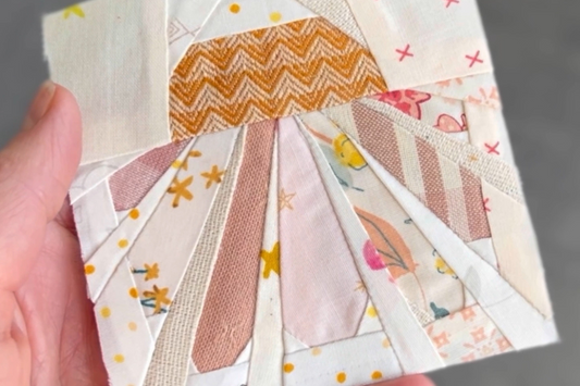Foundation Paper Pieced Daisy Quilt Block made by Tamara Darragh for Remi Vail Studio. Fabrics are varied in pink and orange with floral and plaid.