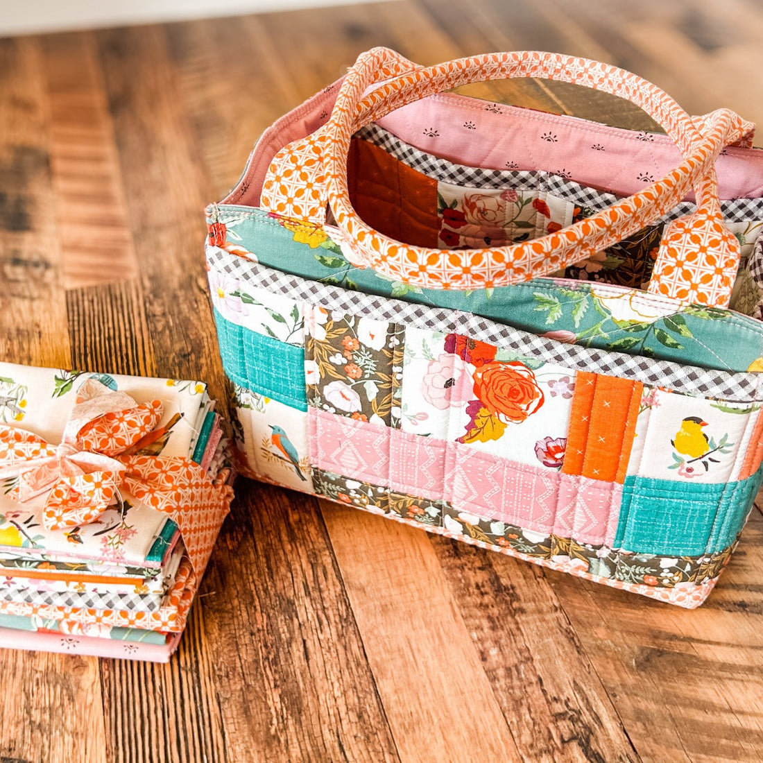 Quilted Maggie Poppins Tote bag by Remi Vail Studio with patchwork pockets made from Winged Medley fabric, flat lay on wooden surface.