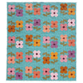 A rectangle Mary Golden Quilt by Remi Vail Studio featuring floral patchwork with four-petal flowers in pink, orange, yellow, purple on a turquoise blue background.