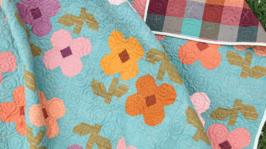 Close-up of the Mary Golden Quilt Pattern by Remi Vail Studio featuring colorful flower blocks, textured quilting, and the pieced quilt backing.