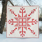 Red geometric quilt on a snowy landscape with trees