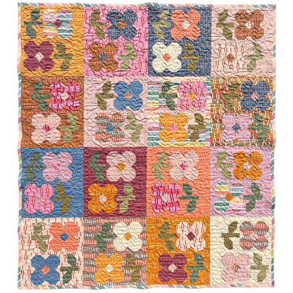 A Mix and Match Version Mary Golden Quilt by Remi Vail Studio with a floral design, featuring multiple colorful patchwork squares with flowers, leaves, and geometric patterns in pink, orange, blue, yellow, and purple.