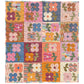 A Mix and Match Version Mary Golden Quilt by Remi Vail Studio with a floral design, featuring multiple colorful patchwork squares with flowers, leaves, and geometric patterns in pink, orange, blue, yellow, and purple.