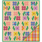 A square quilt or blanket design shown flat against a white background. The product features a beige dotted base with a grid of colorful flower motifs in yellow, blue, pink, purple, and red, plus green leaves.