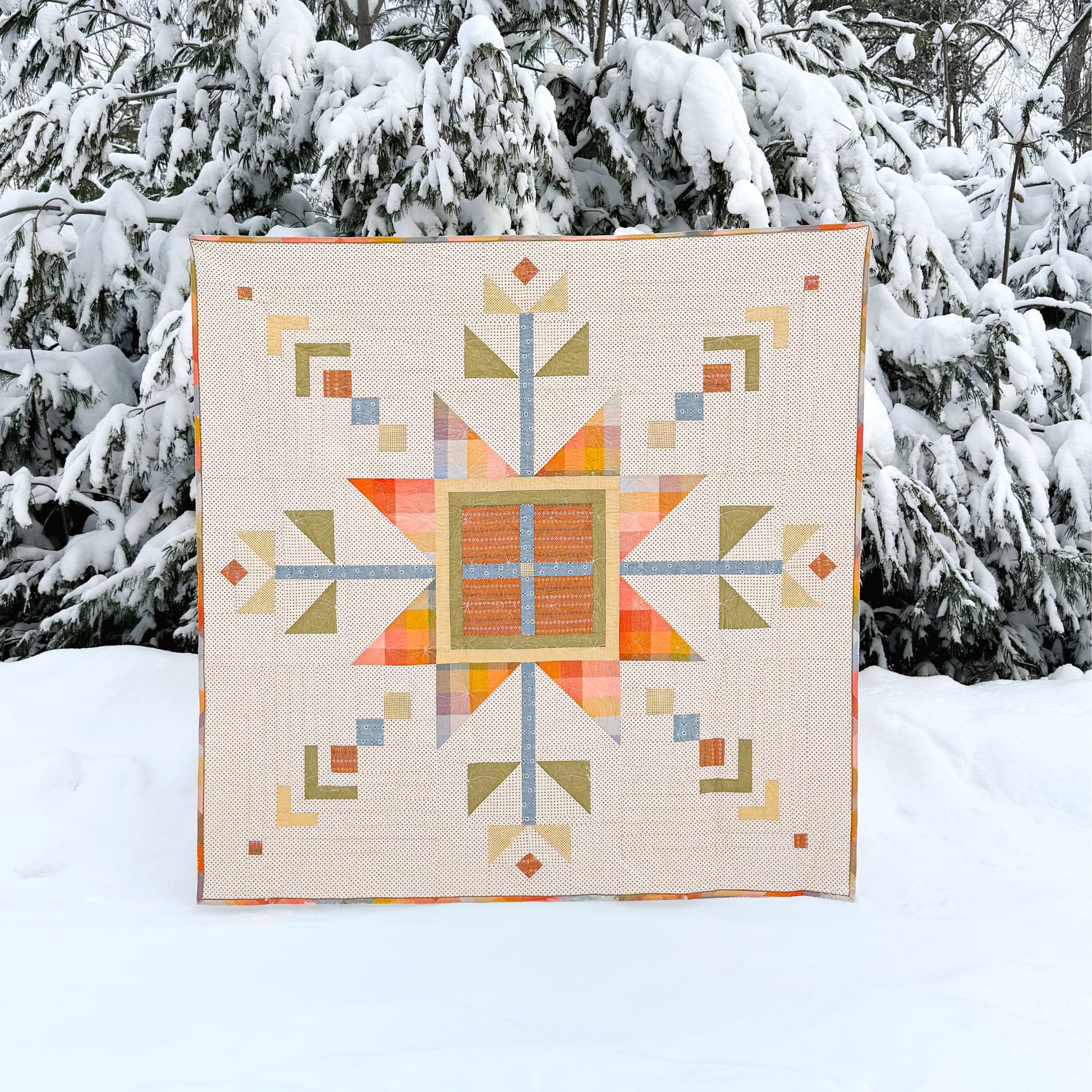 Colorful geometric quilt displayed outdoors in a snowy landscape
