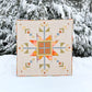 Colorful geometric quilt displayed outdoors in a snowy landscape