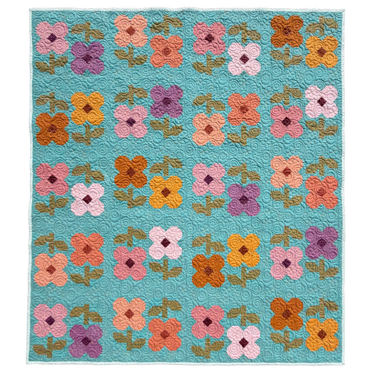 A rectangle Mary Golden Quilt by Remi Vail Studio featuring floral patchwork with four-petal flowers in pink, orange, yellow, purple on a turquoise blue background.