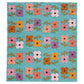 A rectangle Mary Golden Quilt by Remi Vail Studio featuring floral patchwork with four-petal flowers in pink, orange, yellow, purple on a turquoise blue background.