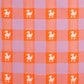 A close-up of a woven textile pattern featuring alternating lavender and orange checkered squares, with small white duck motifs centered on the orange squares.
