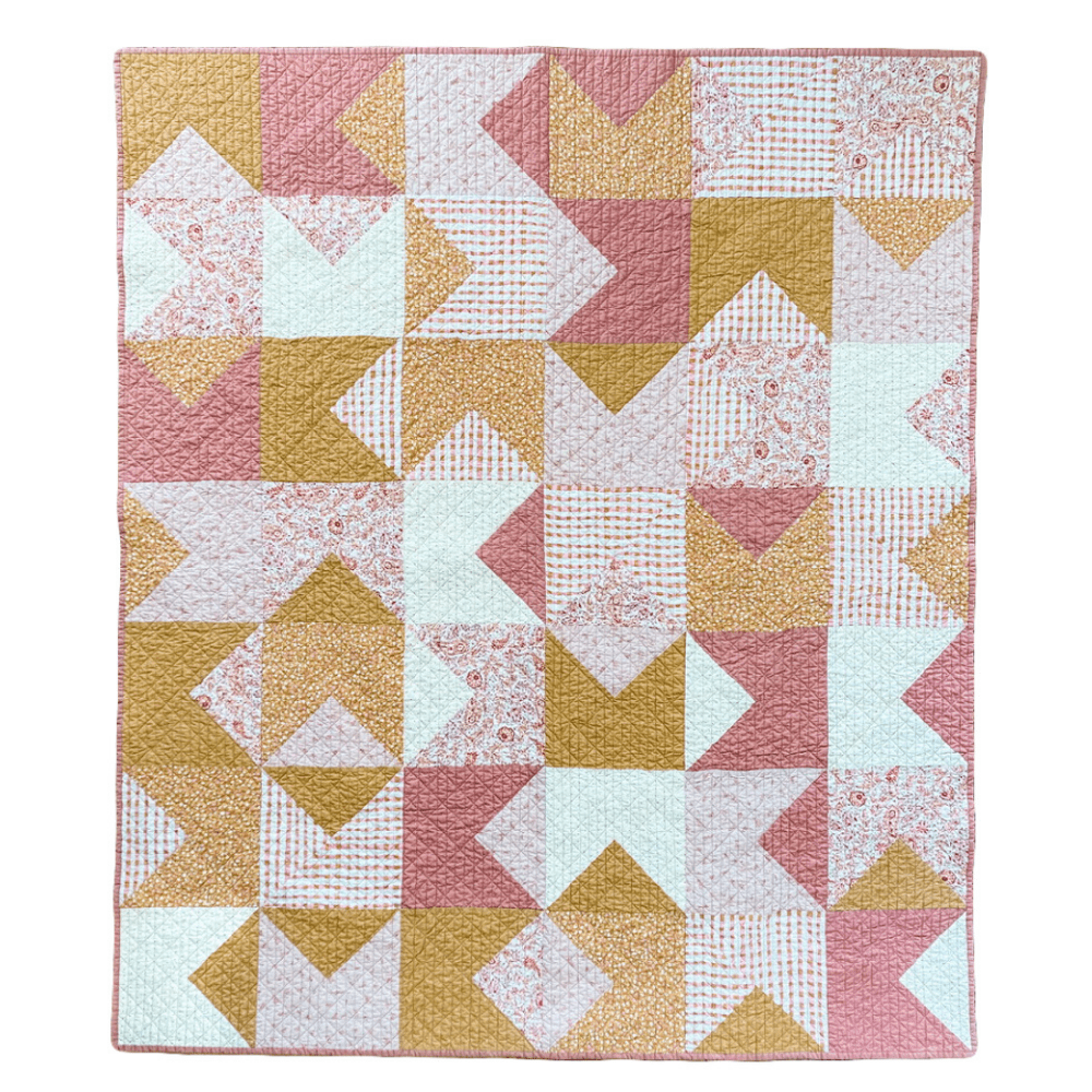 Love notes quilt flat lay on white background in colors of pink, white, and mustard yellow.