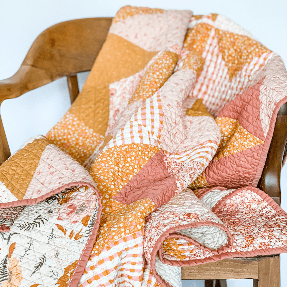 Love Notes Quilt draped over a walnut wooden chair.