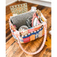 A Patchwork Pockets version of the Maggie Poppins Tote made with yarn dyed wovens in pink, blue, yellow, red, and olive sitting on a wooden floor filled with sewing supplies.