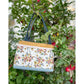 A Maggie Poppins Tote made with pink, brown, rust, white, and black floral fabric hanging from an apple tree.