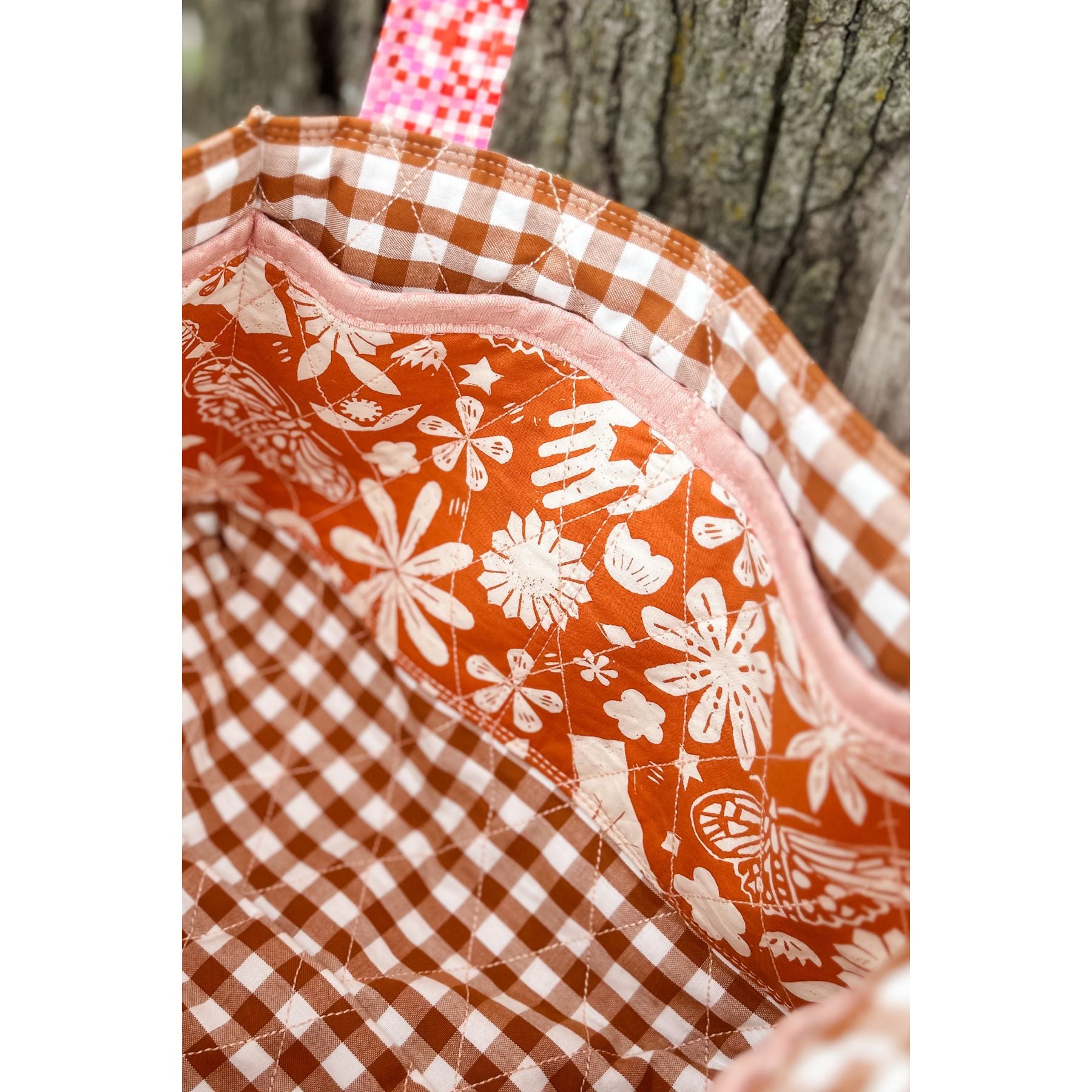 Inside of a Maggie Poppins Tote made with brown gingham with pink trim.