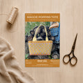 Maggie Poppins tote pattern booklet with a woven bag, scissors, and thread on a wooden surface