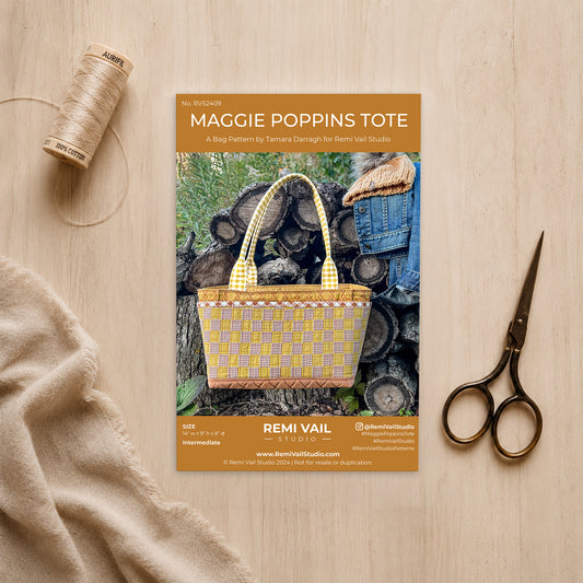 Maggie Poppins tote pattern booklet with a woven bag, scissors, and thread on a wooden surface