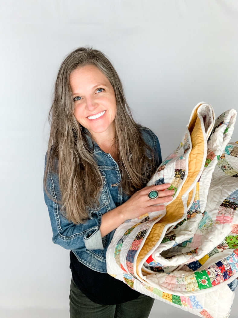 Tamara Darragh of Remi Vail Studio holding a vintage quilt