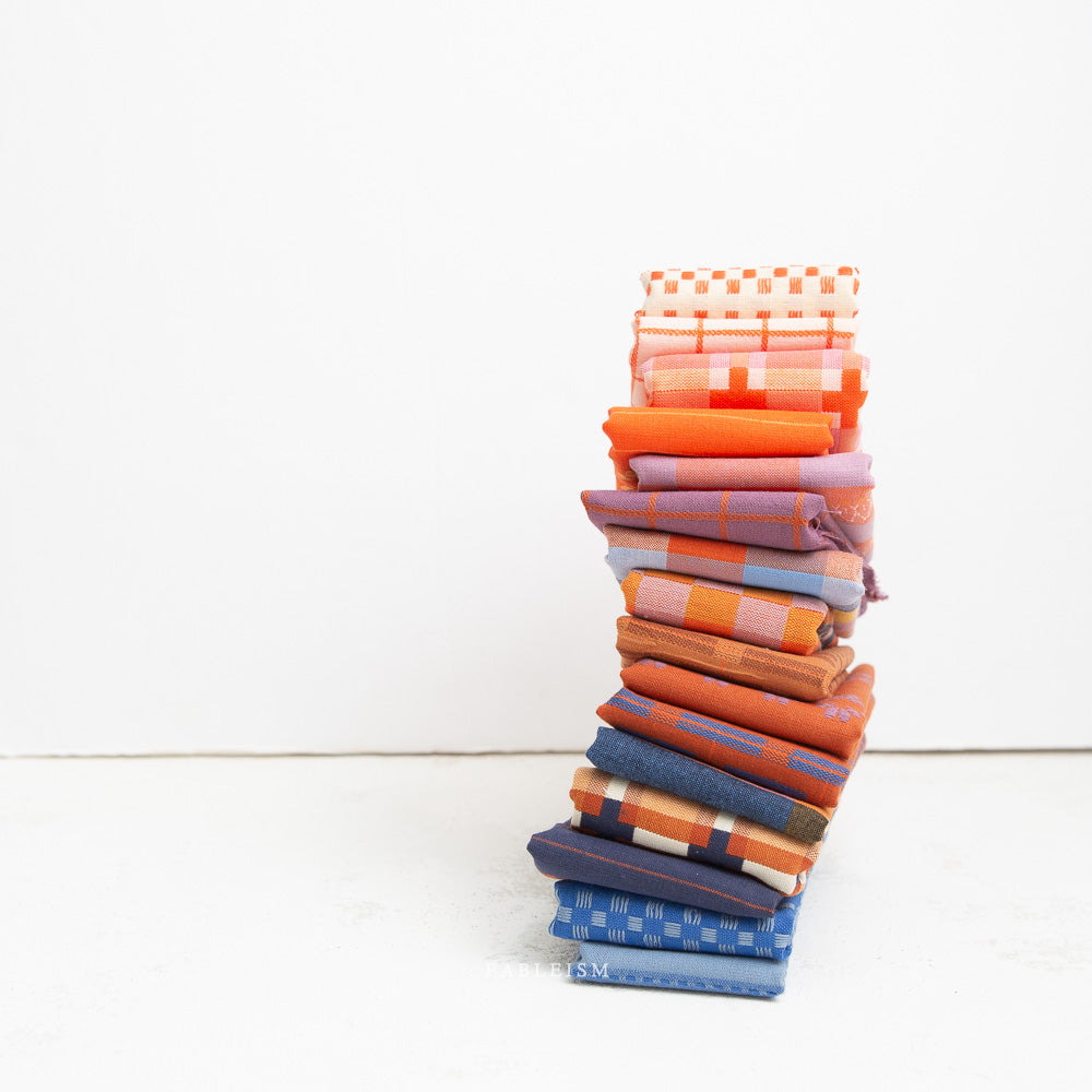 Stack of colorful folded fabric swatches on a white background